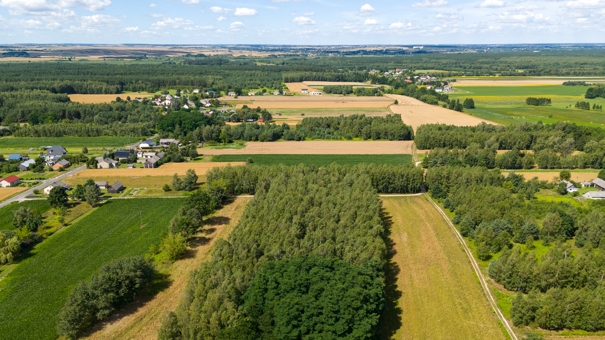 Zdjęcie ilustracyjne do artykułu - ujęcie z lotu ptaka, w tle pola i lasy oraz zabudowania